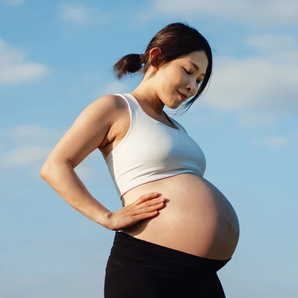 Pregnant lady smiling down on her stomach.