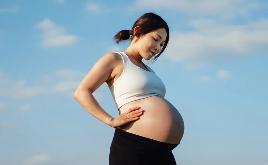 Pregnant lady smiling down on her stomach.